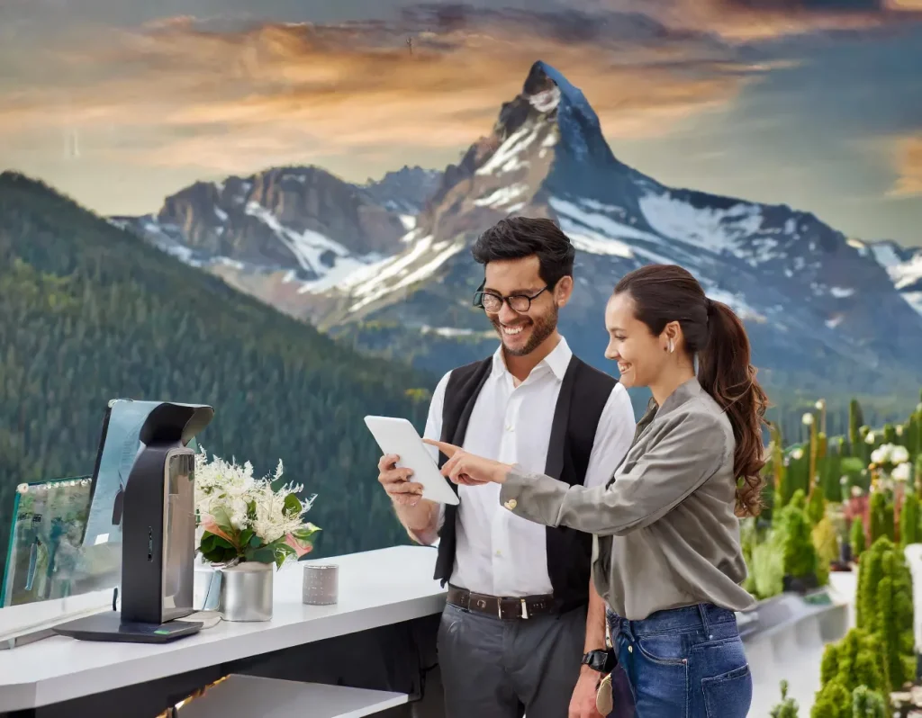 Two people using a tablet at a point of sale with a mountain landscape in the background.